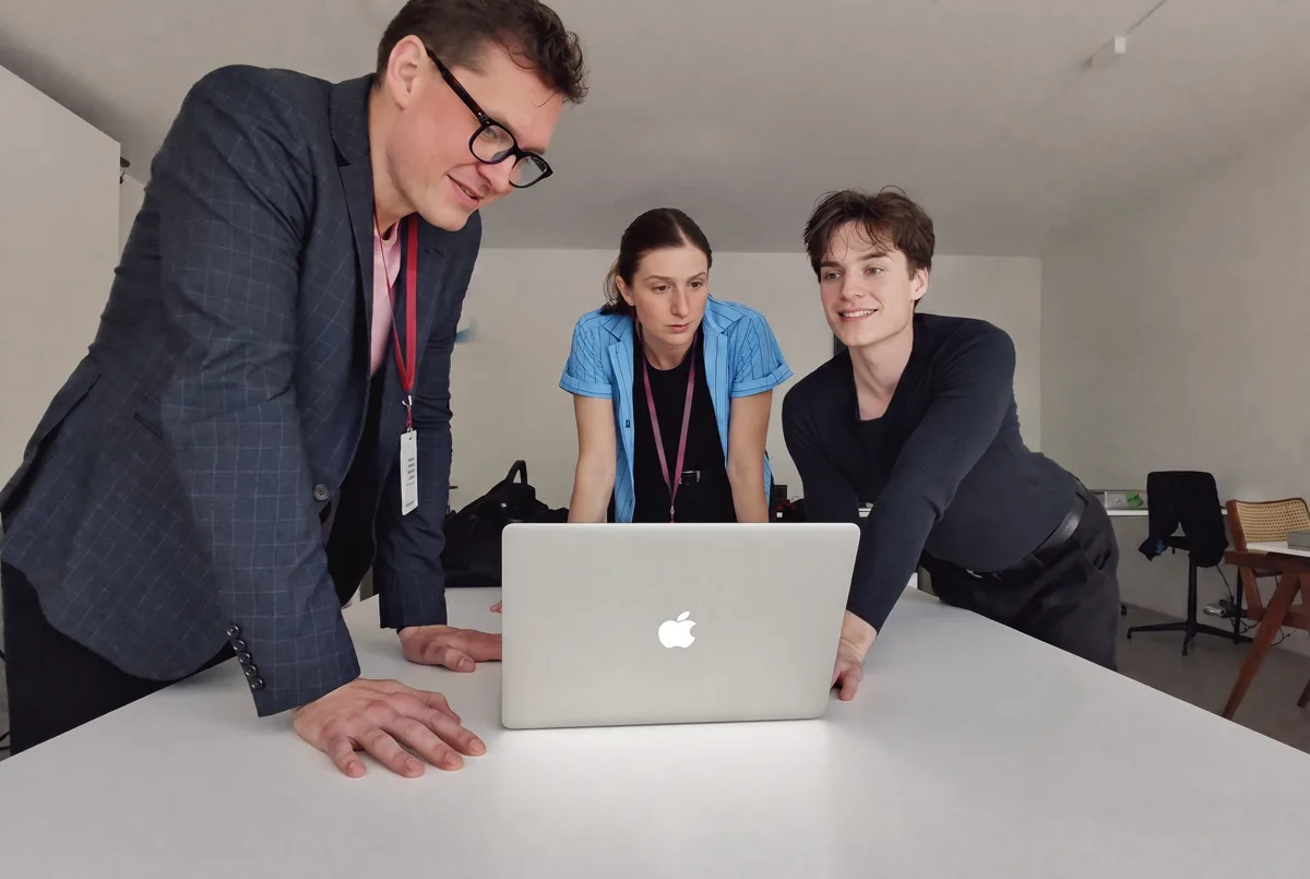 A weekly numbers review: three people leaning over one laptop, going through store metrics together