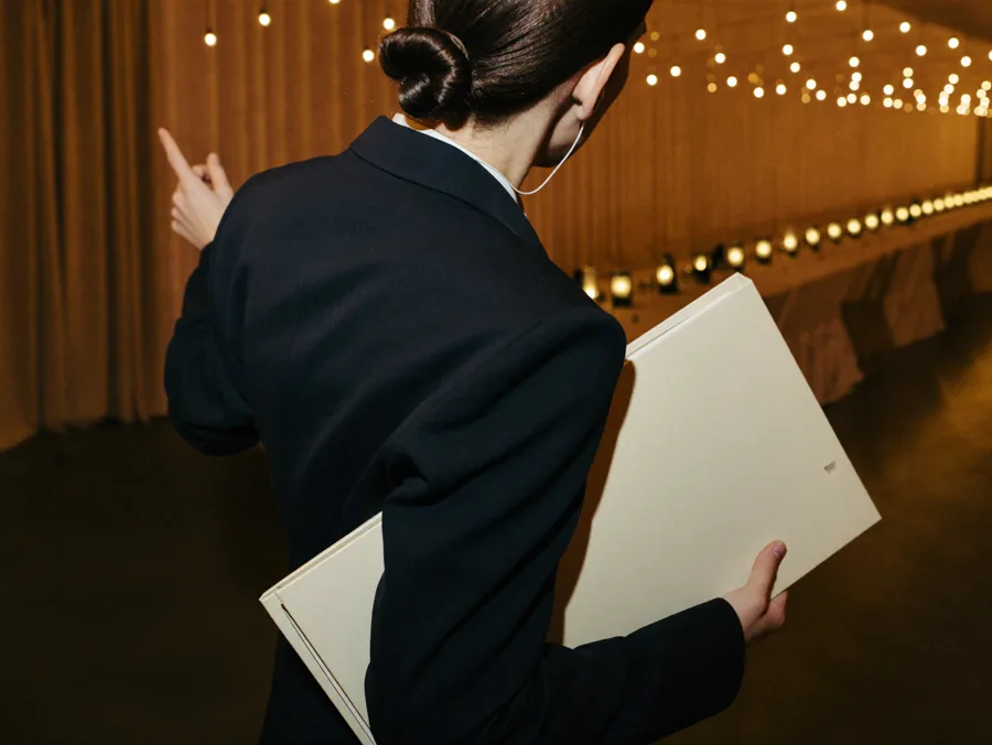 Event planner seen from behind giving final directions across a candlelit reception hall
