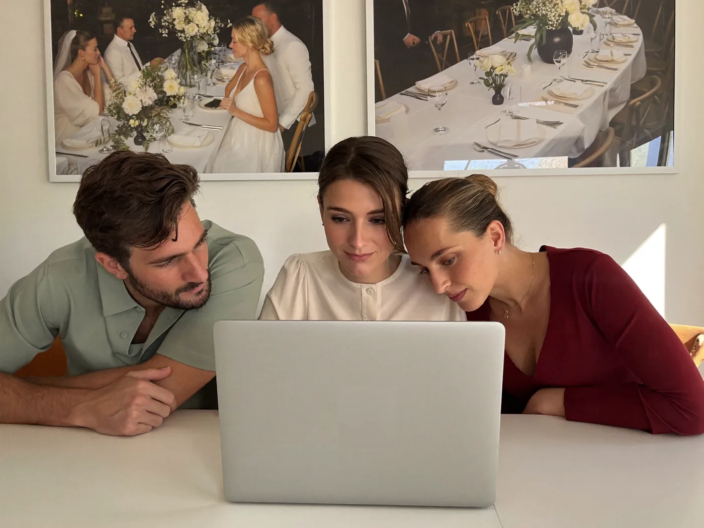 Three people reviewing one laptop screen together in a bright event-design studio