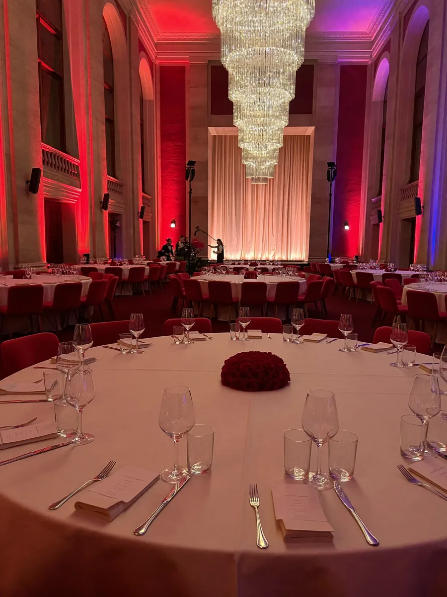 Hotel ballroom set for a gala with burgundy uplighting and crystal chandeliers
