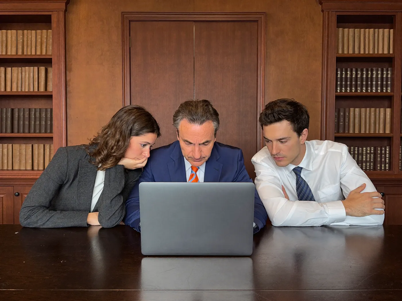 Three attorneys reviewing campaign numbers together on one laptop