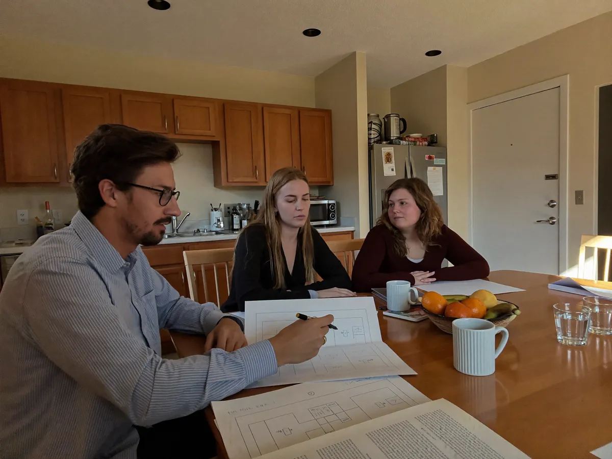 A kitchen-table consult over printed floor plans